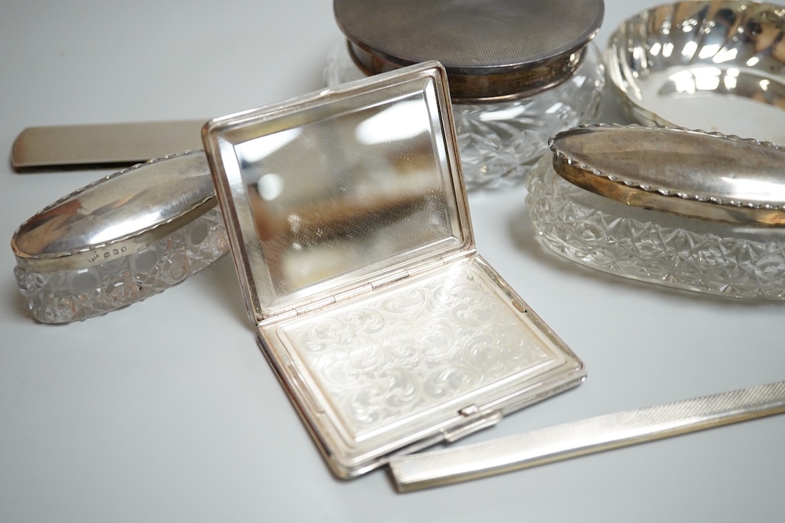 An 835 standard engine turned white metal powder compact, 72mm, three silver mounted glass toilet jars, two silver mounts and an Italian 800 standard small dish.